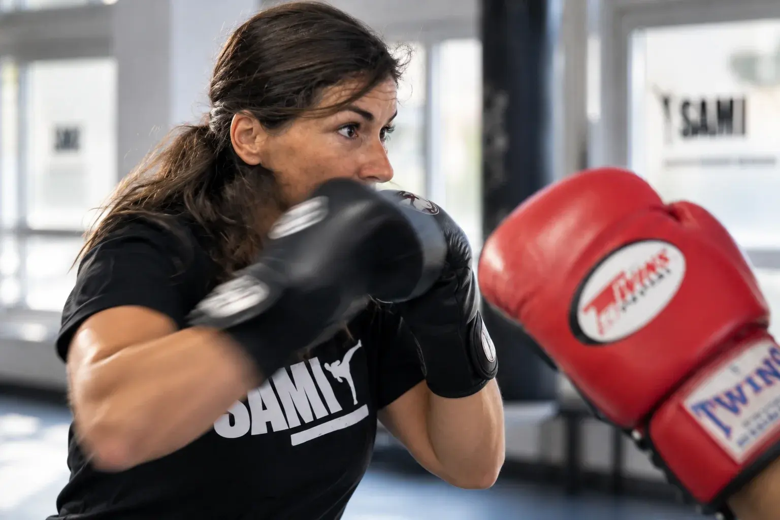 Eine Frau übt mit Boxhandschuhen Schläge auf die Pratzen ihres Trainingspartners