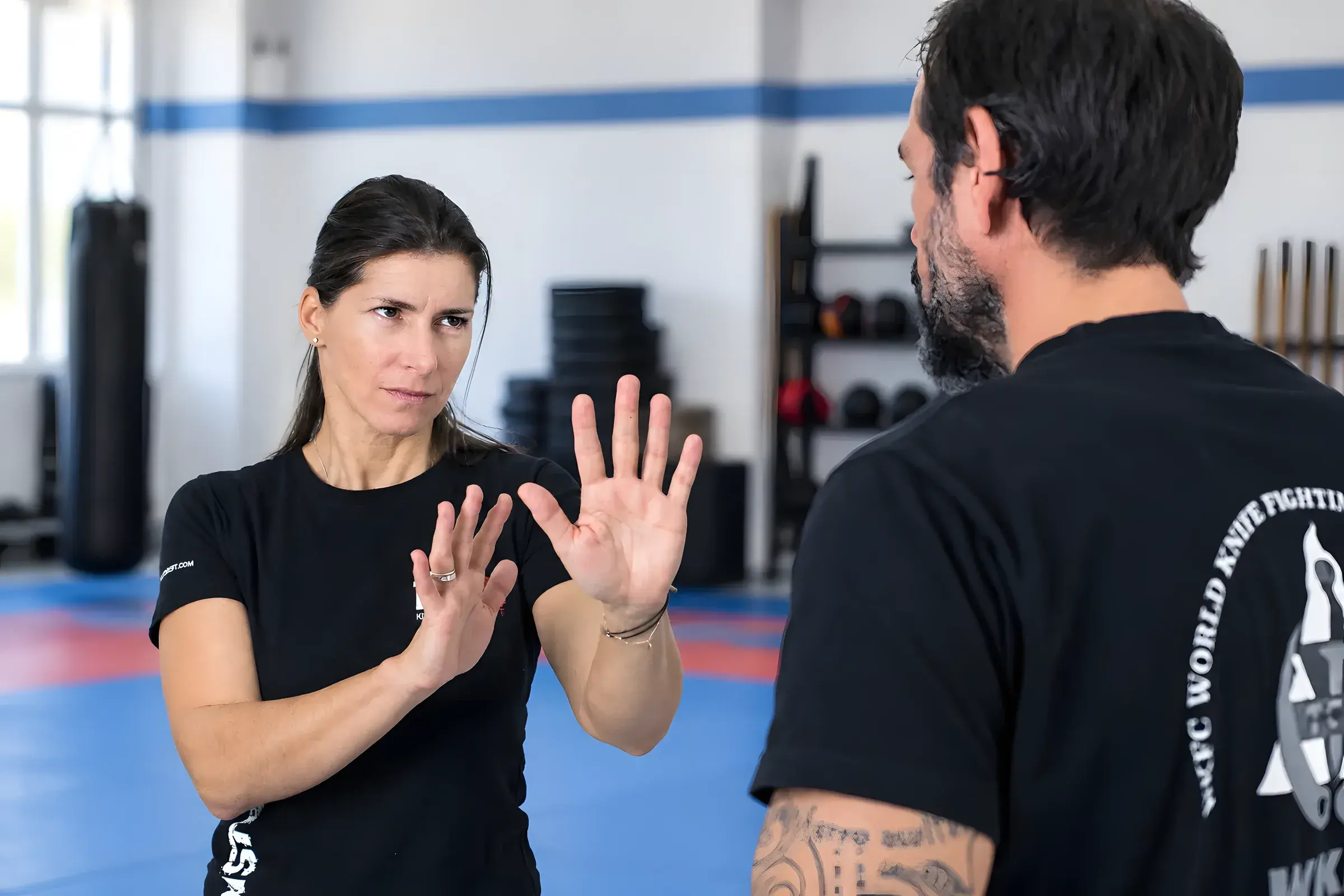 Eine Frau hebt abwehrend beide Hände vor einem Trainingspartner