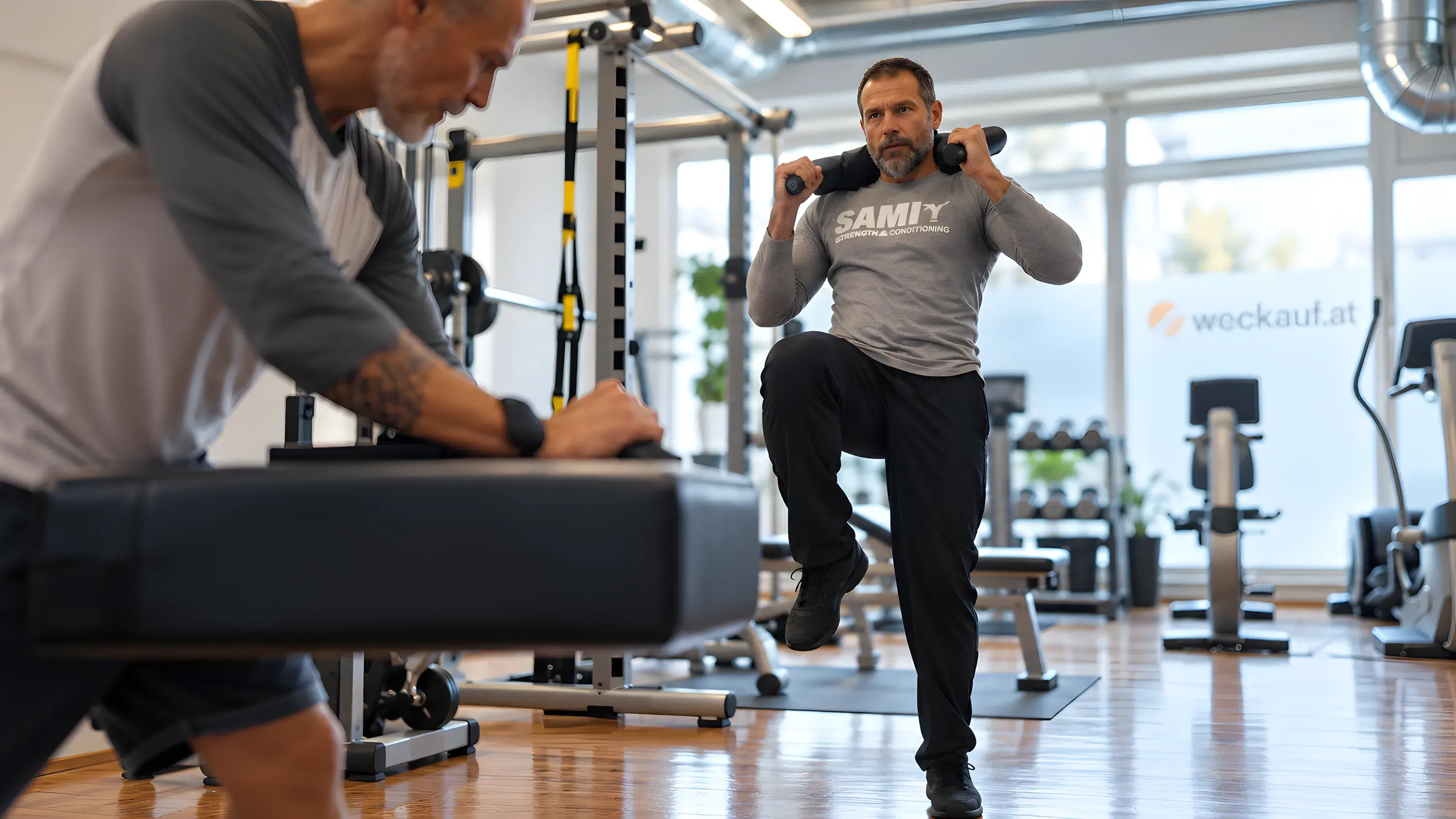 Ein Kunde hebt im Functional Training das Knie, Peter Weckauf im Vordergrund