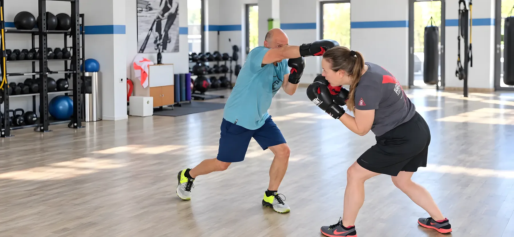Zwei Personen üben Schrittarbeit und Deckung mit Boxhandschuhen