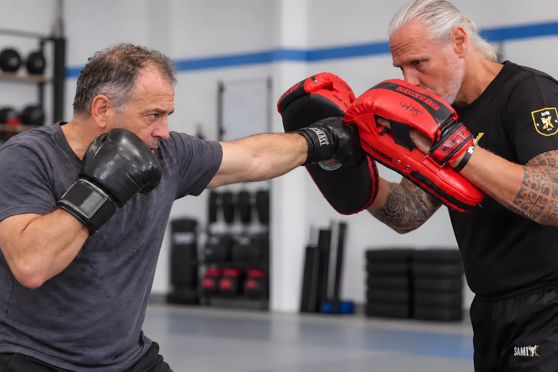 Pratzentraining: Ein Mann schlägt mit Boxhandschuhen auf die Pratzen seines Coaches