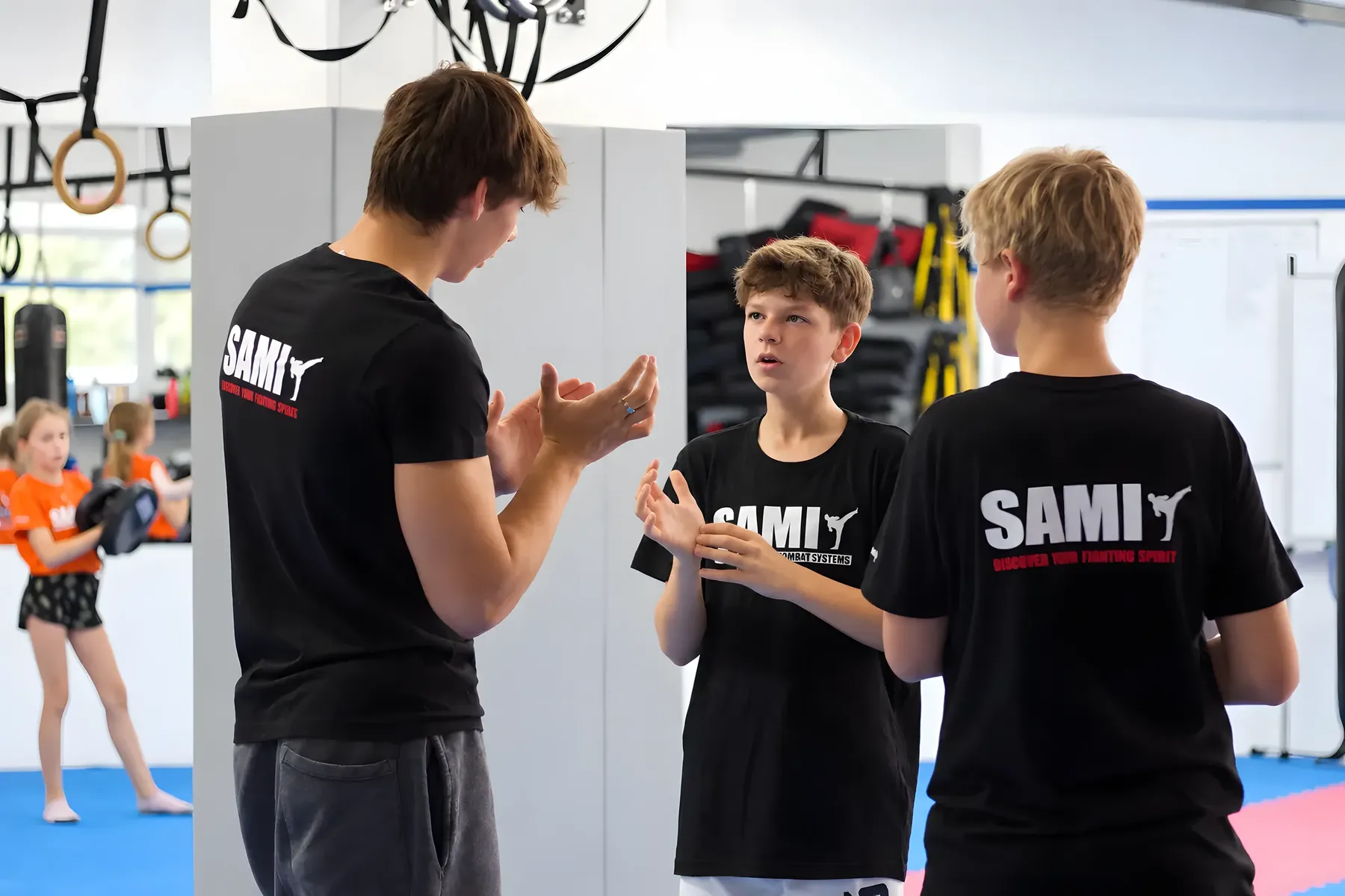 Ein Trainer erklärt zwei Jugendlichen eine Übung